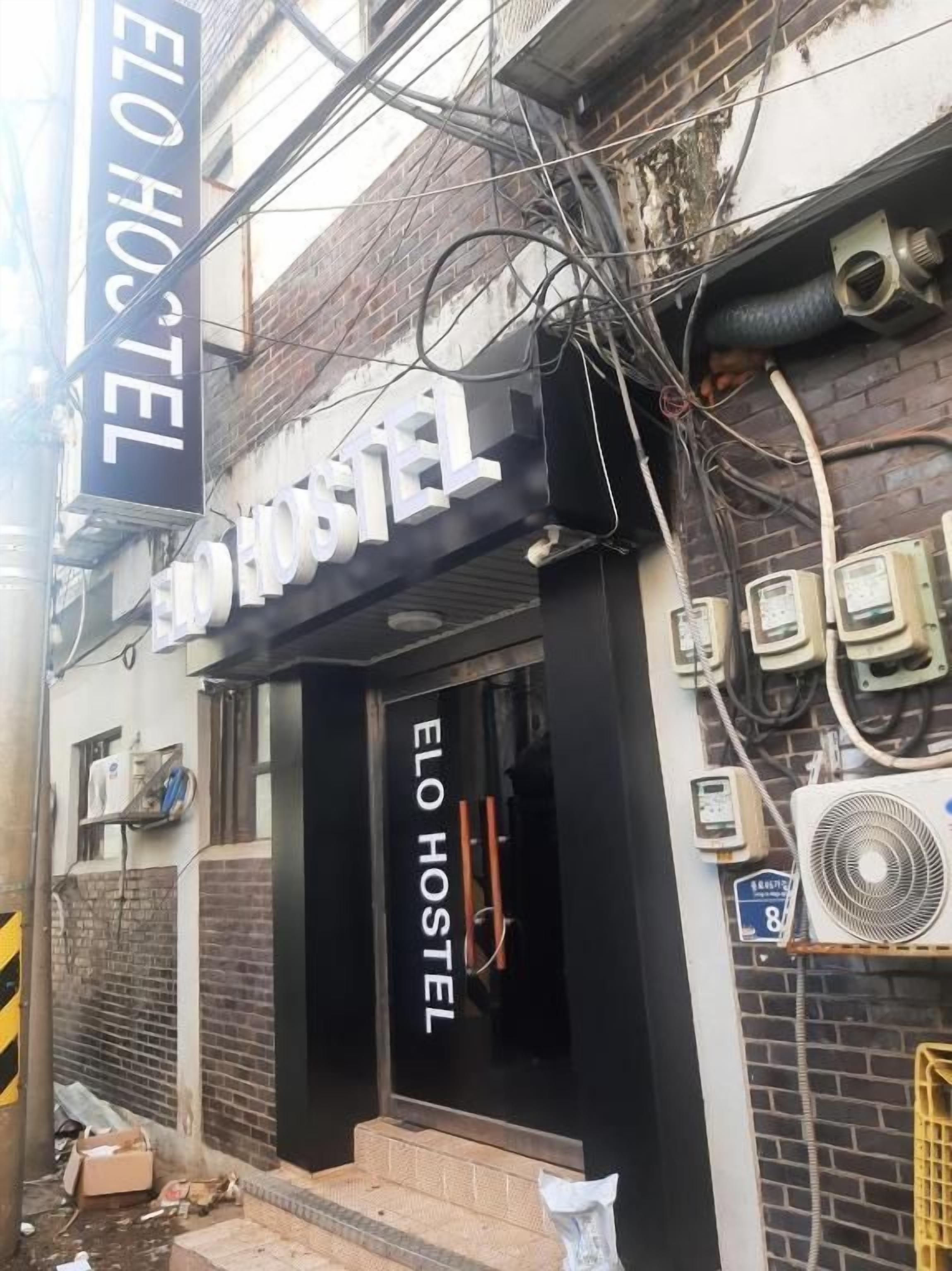 A hostel with a black facade and a sign reading 'ELO HOSTEL'.