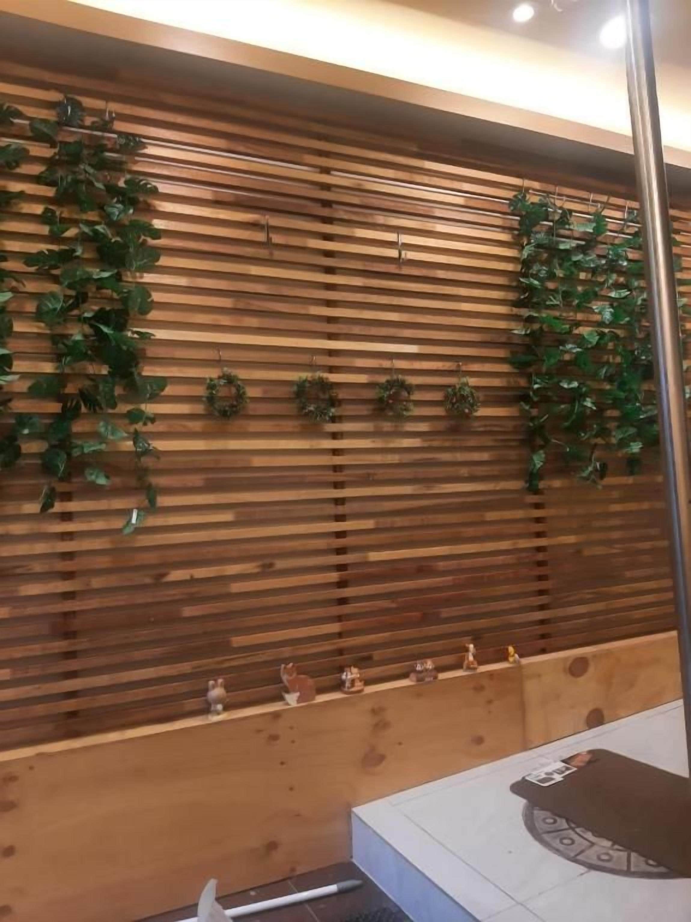 A wooden wall with horizontal slats, green foliage, and small figurines.