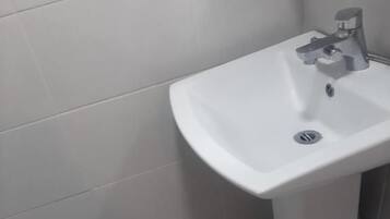 A bathroom with a white sink, a mirror, and a tiled floor.