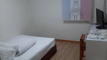 A bedroom with a bed, a desk, a chair, a computer, and an air conditioning unit.
