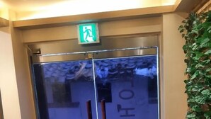 Porta de elevador de vidro com um sinal de saída de emergência verde acima.
