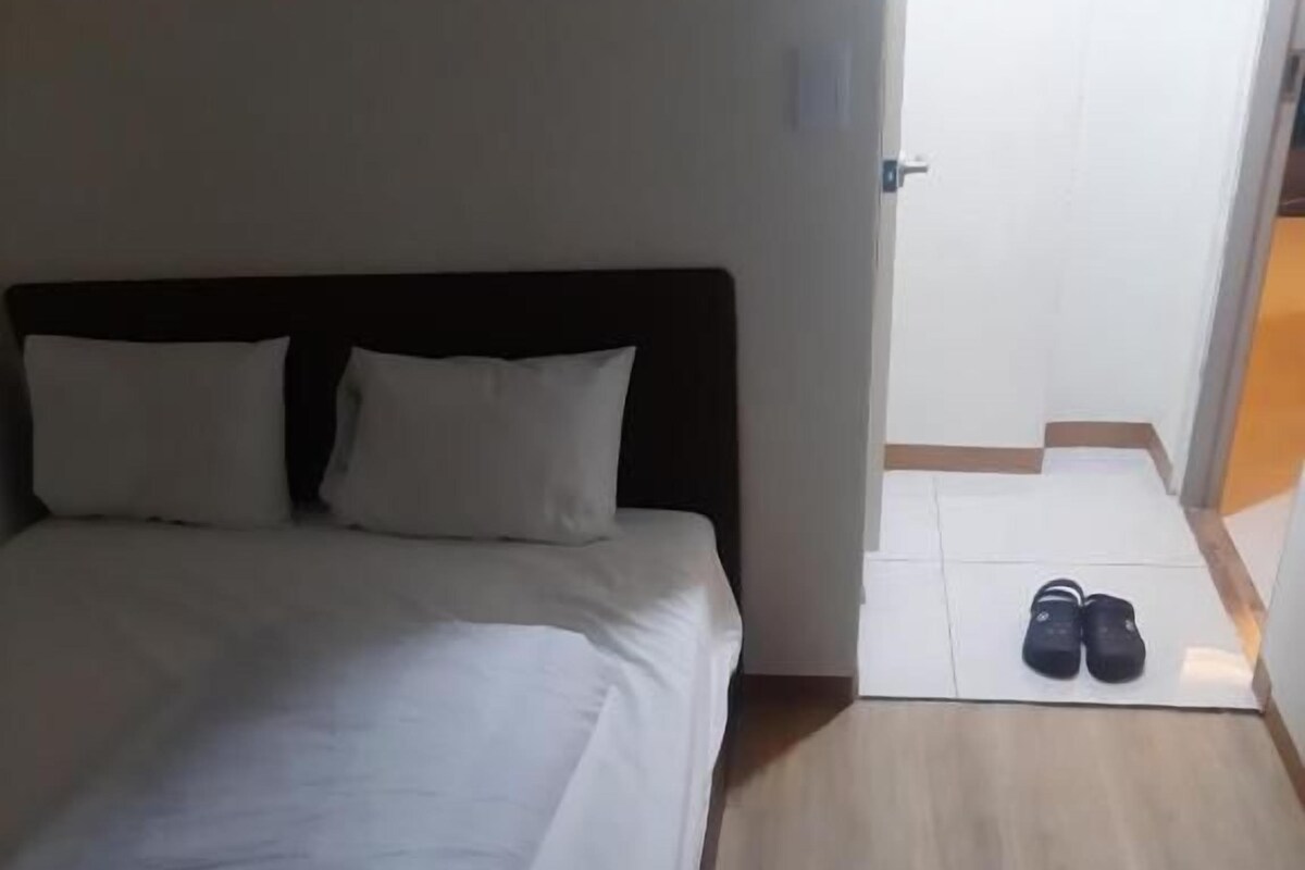 Ein Hotelzimmer mit einem Bett, einem Schuhpaar auf dem Boden und einer Tür zu einem anderen Raum.
