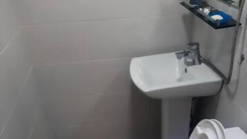 A bathroom with a toilet, sink, and a shower area.