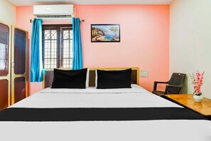 A hotel room with a bed, a desk, a chair, a painting on the wall, and a window with curtains. - Collection O Visakhapatnam Bus Terminal (Visakhapatnam)