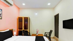 Hotellihuone, jossa on sänky, työpöytä, kaksi tuolia, televisio ja vaatekaappi.