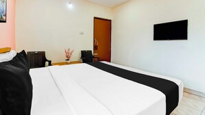 Hotellihuone, jossa on sänky, televisio, työpöytä ja tuoli.