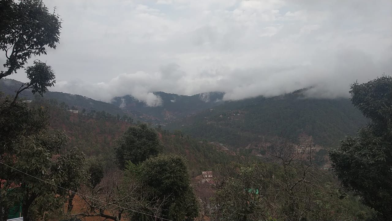 Un paisaje montañoso con vegetación densa y cielo nublado.