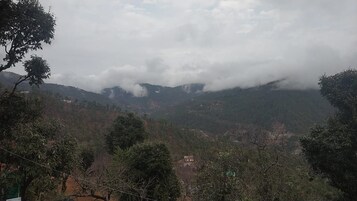 A mountainous landscape with dense vegetation and a cloudy sky.