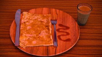 Una mesa de madera con un plato que contiene una tortilla enrollada, un tenedor, un cuchillo y un vaso de jugo de naranja.