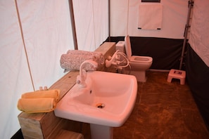 Ein Badezimmer mit Waschbecken, Toilette und einem kleinen Hocker.