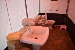 A bathroom with a sink, toilet, and a small stool.
