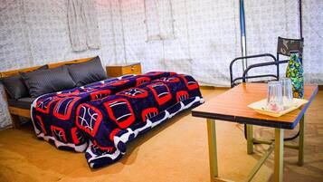 Una habitación con cama, una mesa y una silla. Tiene una pared con diseño y un ventanal con cortinas.