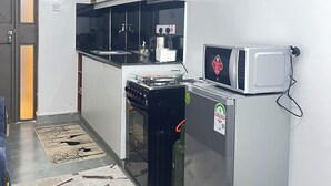 Een kleine keuken met een fornuis, magnetron en een koelkast.