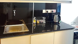 Een keuken met een zwart aanrecht, een roestvrijstalen spoelbak en een koffiezetapparaat.