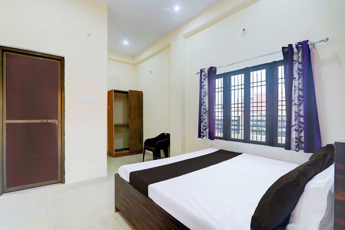 A bedroom with a bed, a wardrobe, a chair, and a window with curtains.