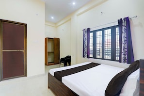 A bedroom with a bed, a wardrobe, a chair, and a window with curtains. - Collection O Varanasi Ashta Bhuji Temple (Varanasi)