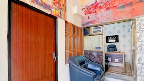 A room with a wooden door, a reception desk, a black leather chair, and a wall with a decorative pattern. - Collection O Varanasi Ashta Bhuji Temple (Varanasi)