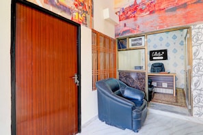 A room with a wooden door, a reception desk, a black leather chair, and a wall with a decorative pattern. - Collection O Varanasi Ashta Bhuji Temple (Varanasi)