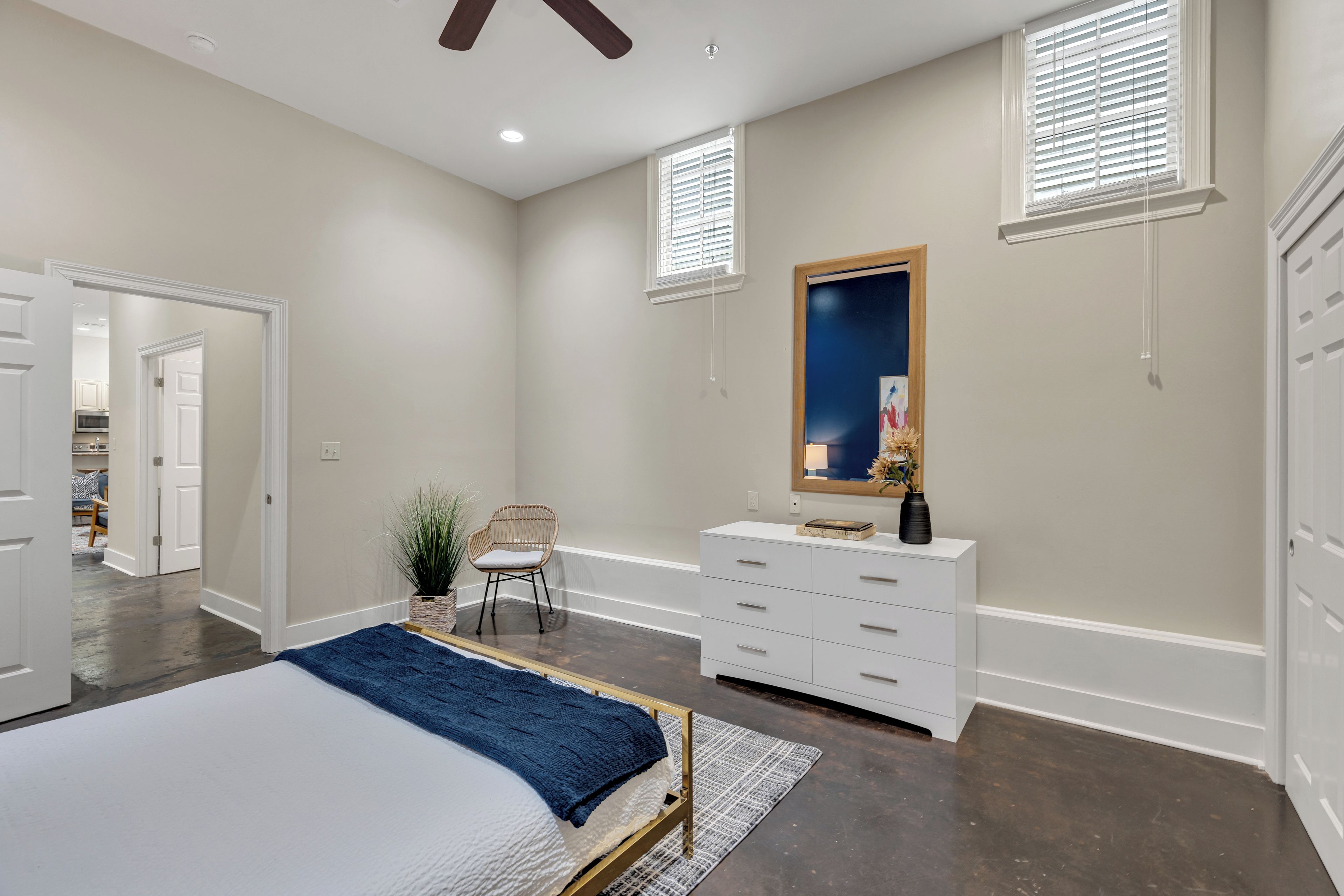 A bedroom with a bed, dresser, chair, and a large mirror.