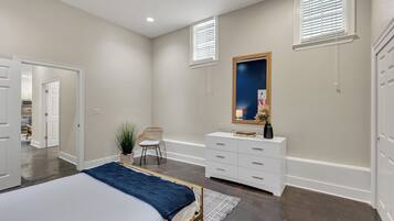 A bedroom with a bed, dresser, chair, and a large mirror.