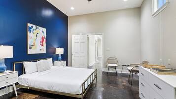 A bedroom with a bed, bedside tables, a chair, a dresser, and a ceiling fan.