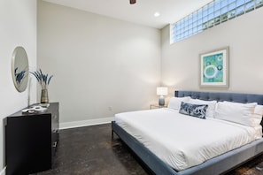 Ein modernes Schlafzimmer mit einem großen Bett, einem Schminktisch, einem Spiegel und einem Gemälde an der Wand.