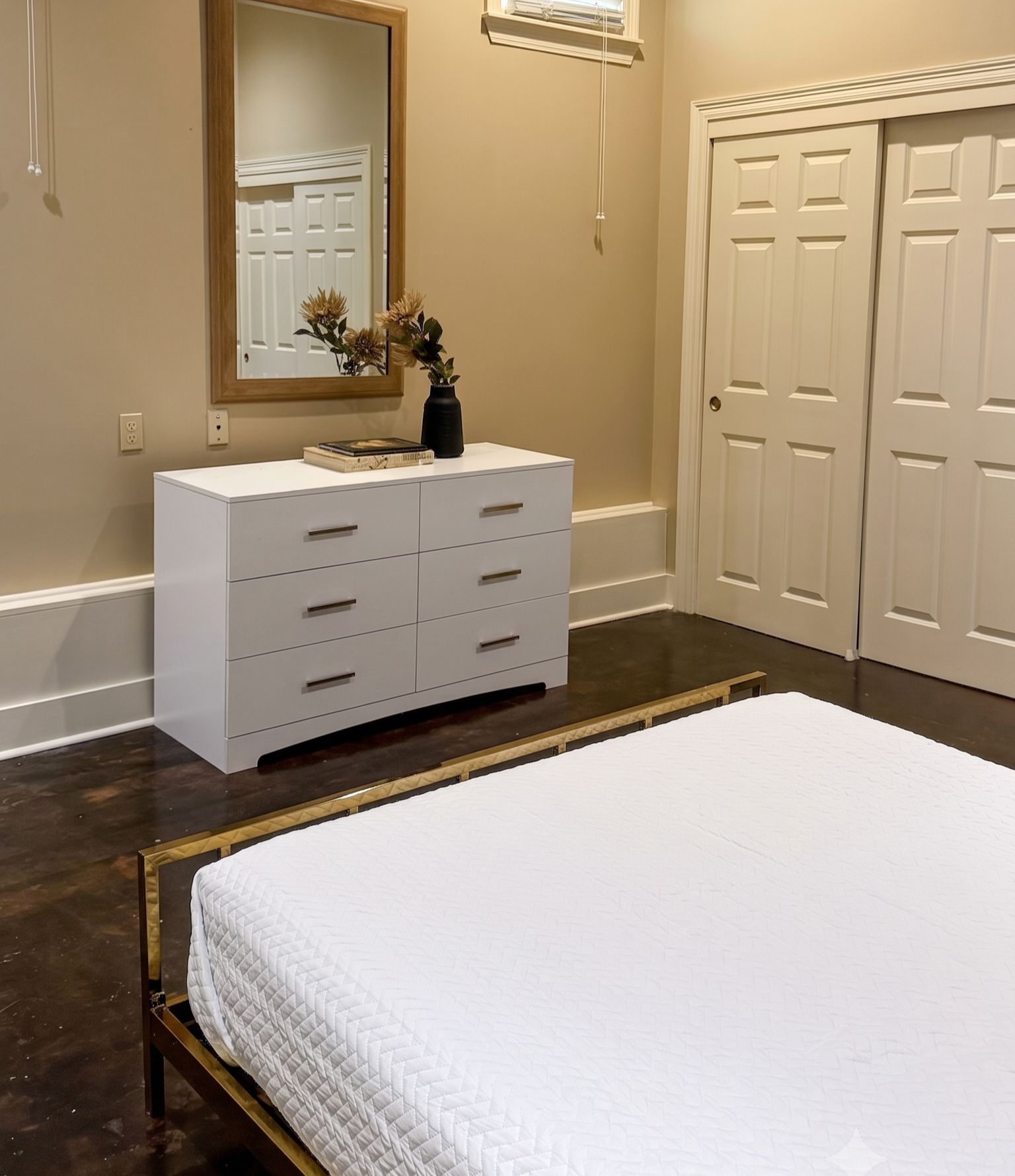 A bedroom with a bed, a dresser, a mirror, and a door.