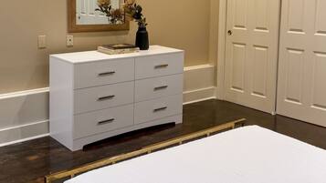 A bedroom with a bed, a dresser, a mirror, and a door.