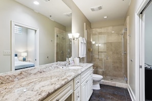 A bathroom with a marble countertop, a glass-enclosed shower, and a toilet. - Historic Bywater 2BR Near Frenchmen St (New Orleans)