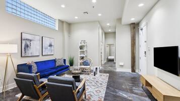 A modern living room with a blue sofa, a coffee table, and a flat-screen TV.