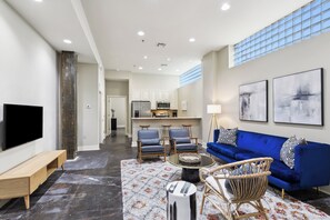 A modern living room with a blue sofa, two armchairs, a coffee table, and a flat-screen TV. - Historic Bywater 2BR Near Frenchmen St (New Orleans)
