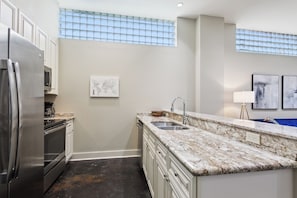 A modern kitchen with stainless steel appliances, a marble countertop, and a window with a grid pattern. - Historic Bywater 2BR Near Frenchmen St (New Orleans)