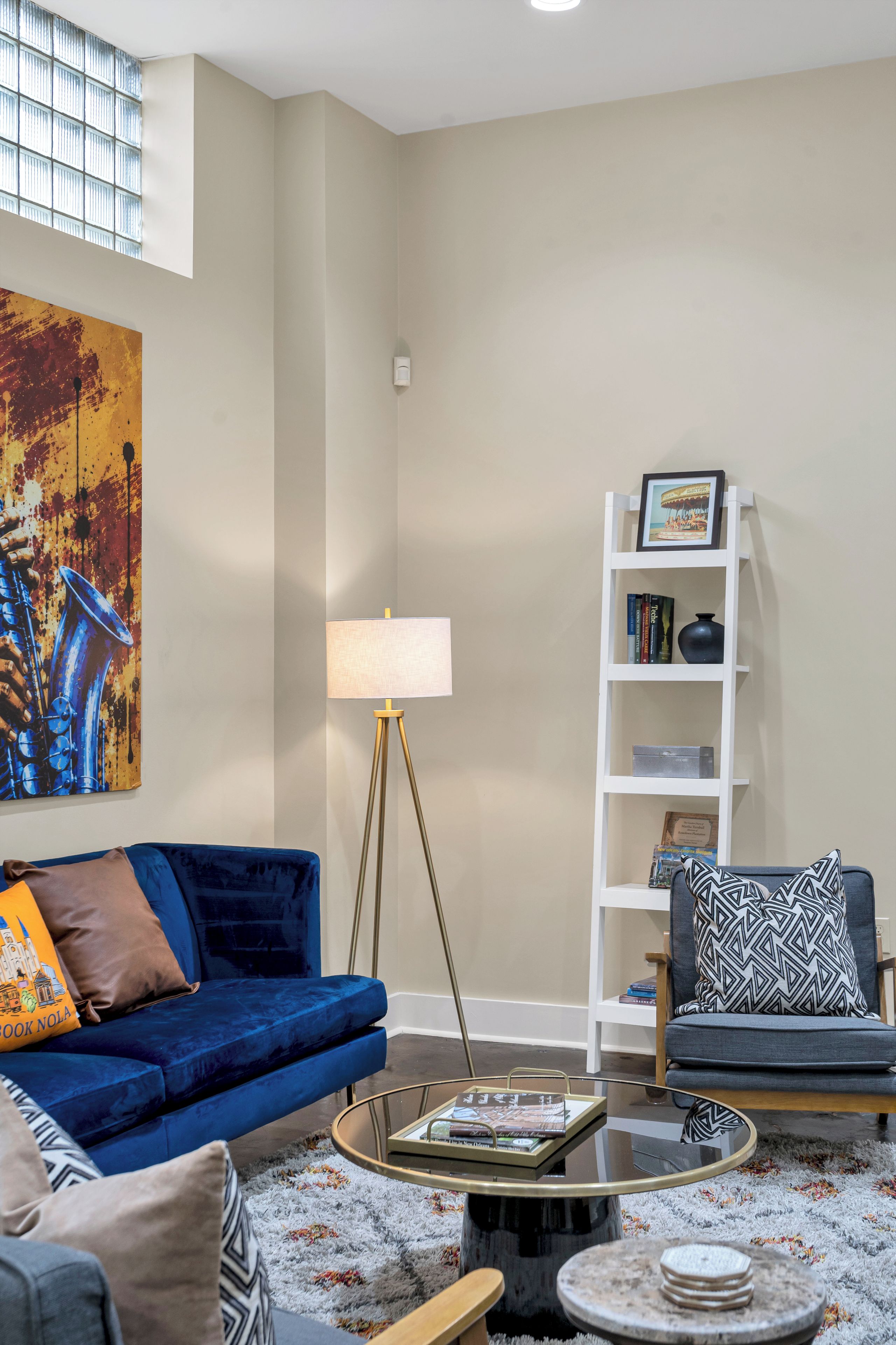 Un salon avec un canapé bleu, une lampe sur pied, une bibliothèque et une table basse.