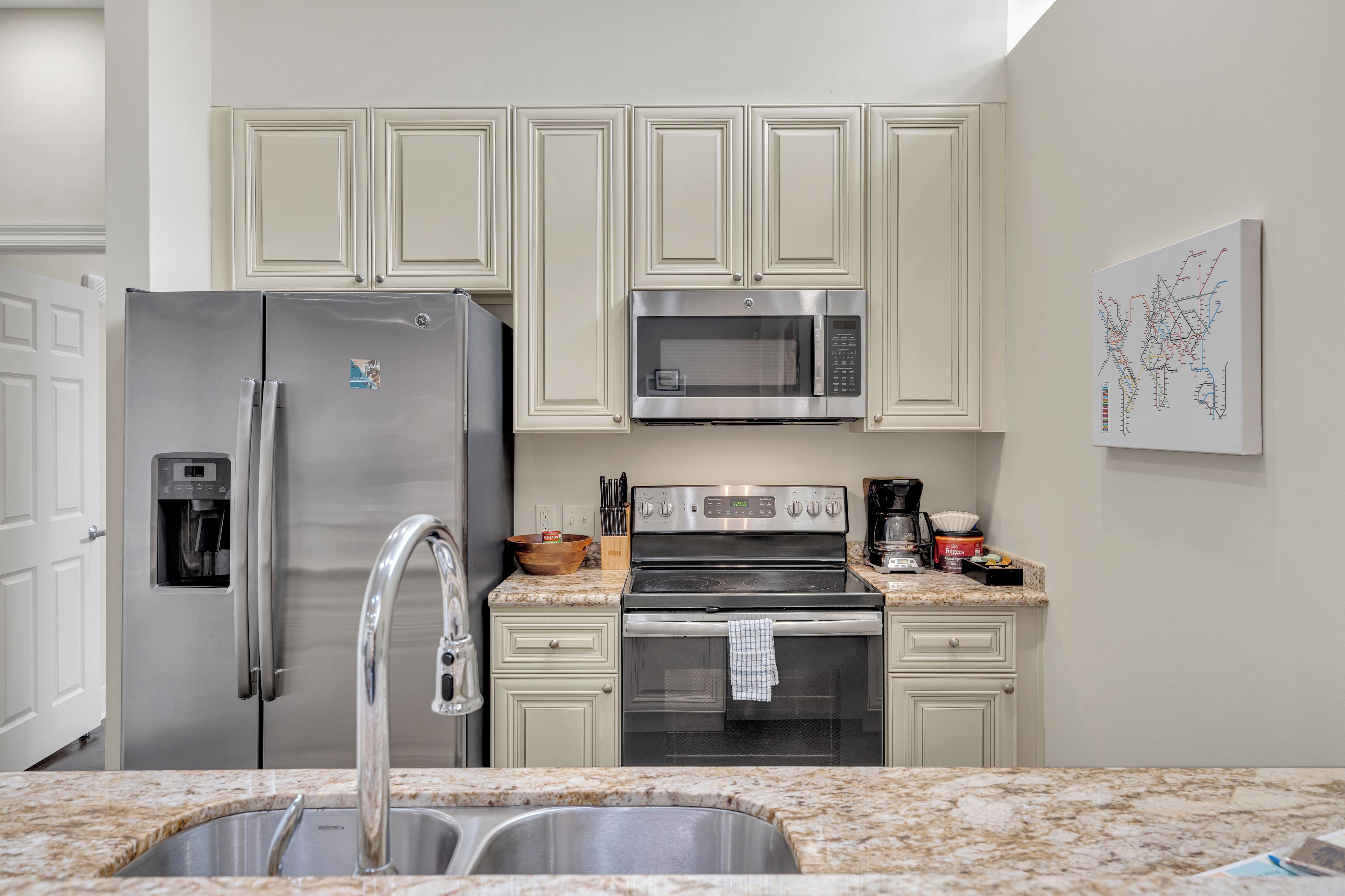 A modern kitchen with stainless steel appliances, a granite countertop, and white cabinetry.