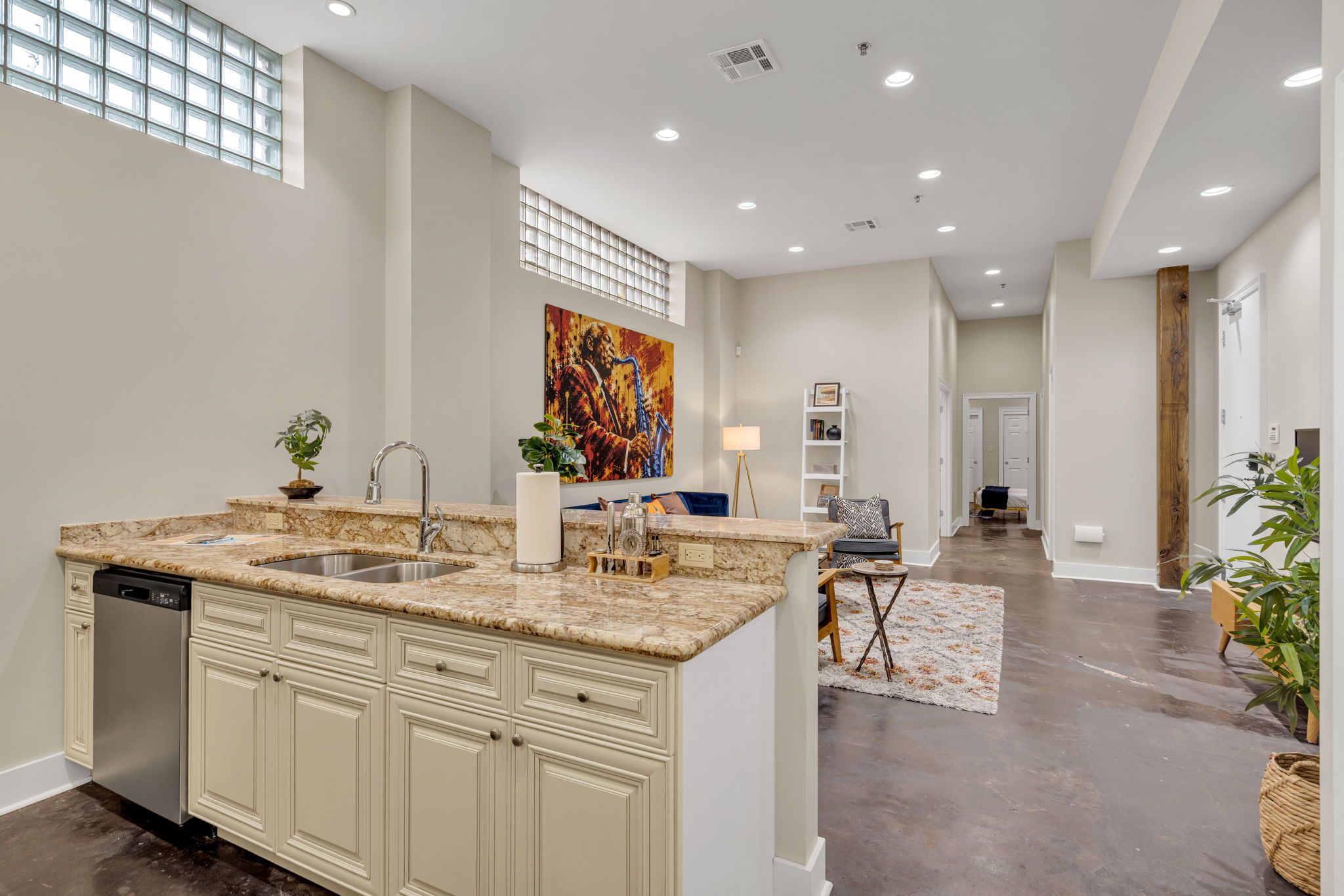 A modern kitchen with a marble countertop, built-in dishwasher, and a large island with a sink.