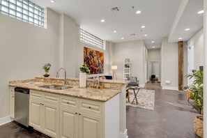 Cozinha moderna com bancada de mármore, lava-louças embutida e uma ilha grande com pia.