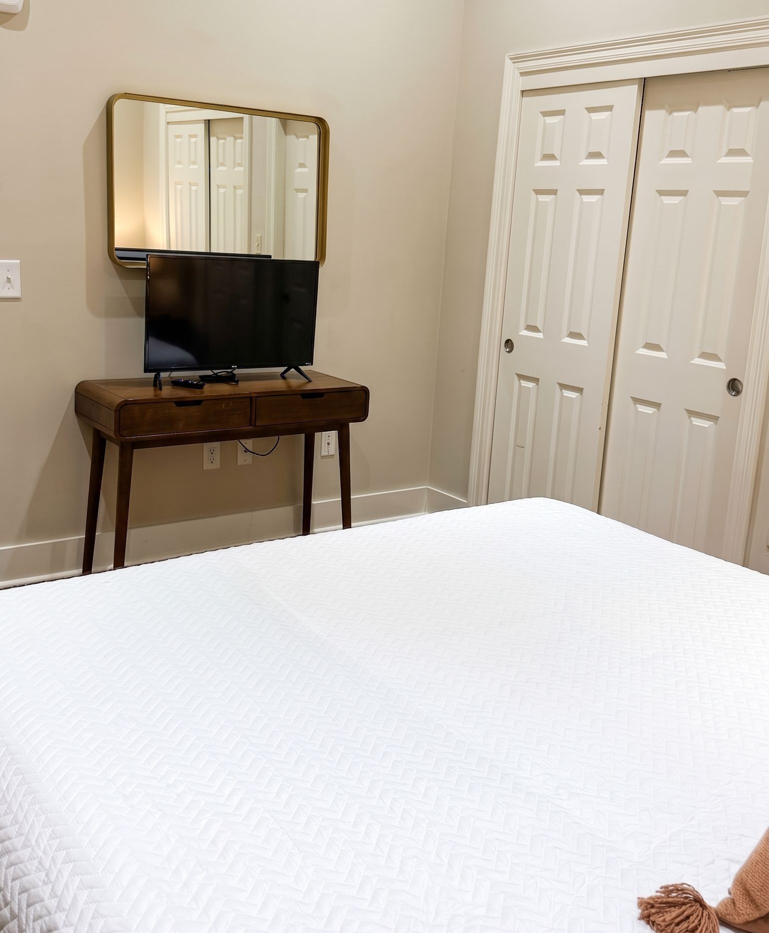 A bedroom with a bed, a bedside table, a TV, and a wardrobe.