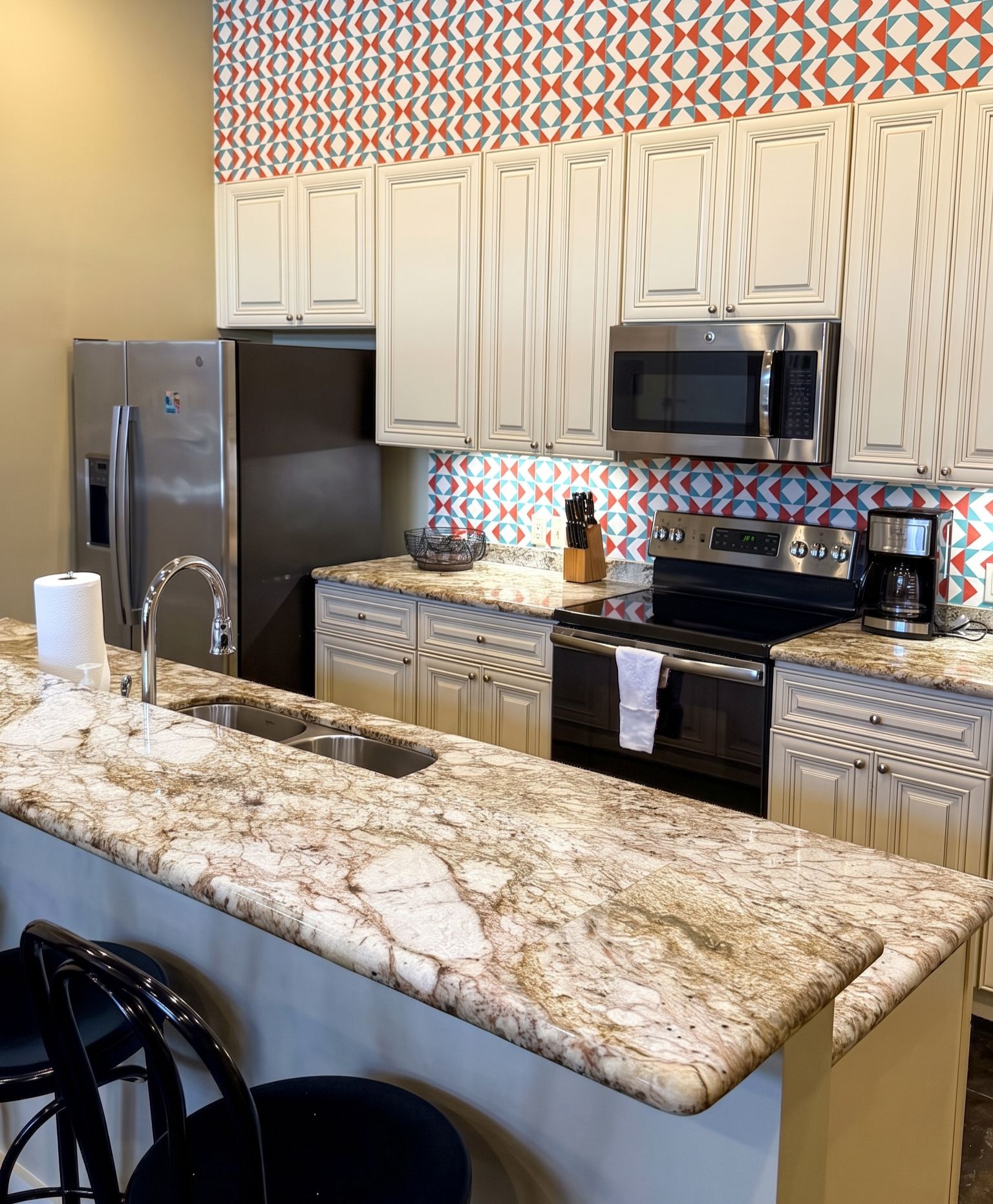 Eine Küche mit Marmorarbeitsplatte, Edelstahlgeräten und einer backsplash mit Muster.