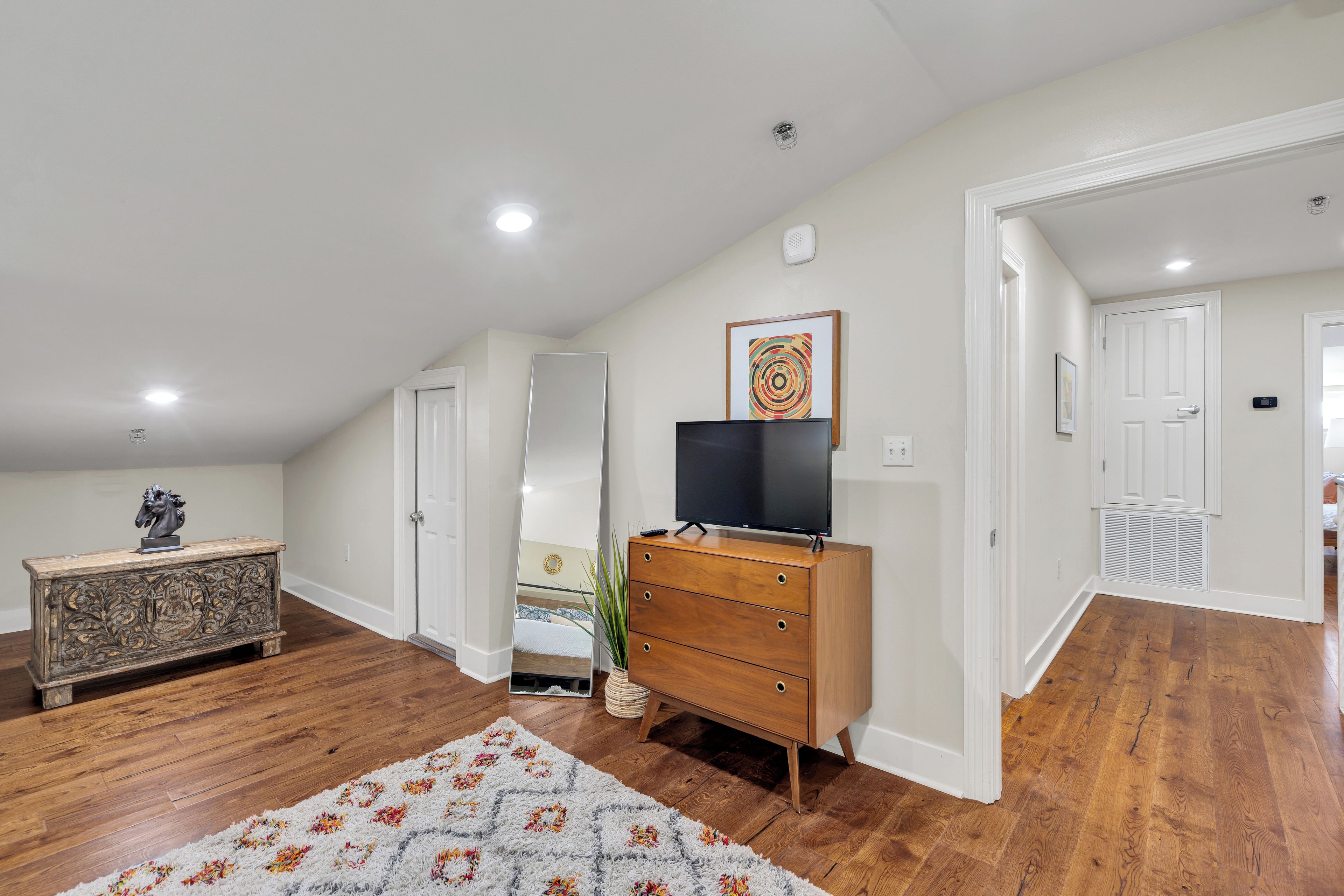 A room with a wooden dresser, a flat-screen TV, a mirror, and a decorative horse head.
