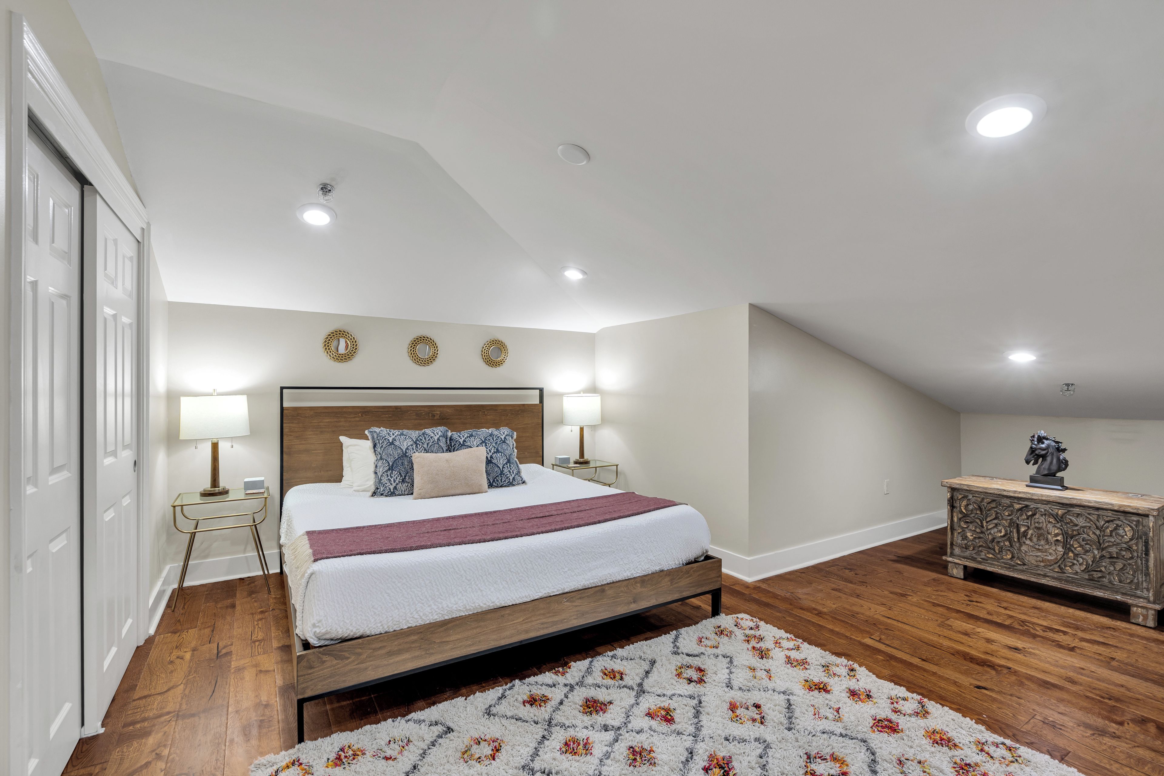 A bedroom with a wooden bed, white walls, and a ceiling with recessed lighting.