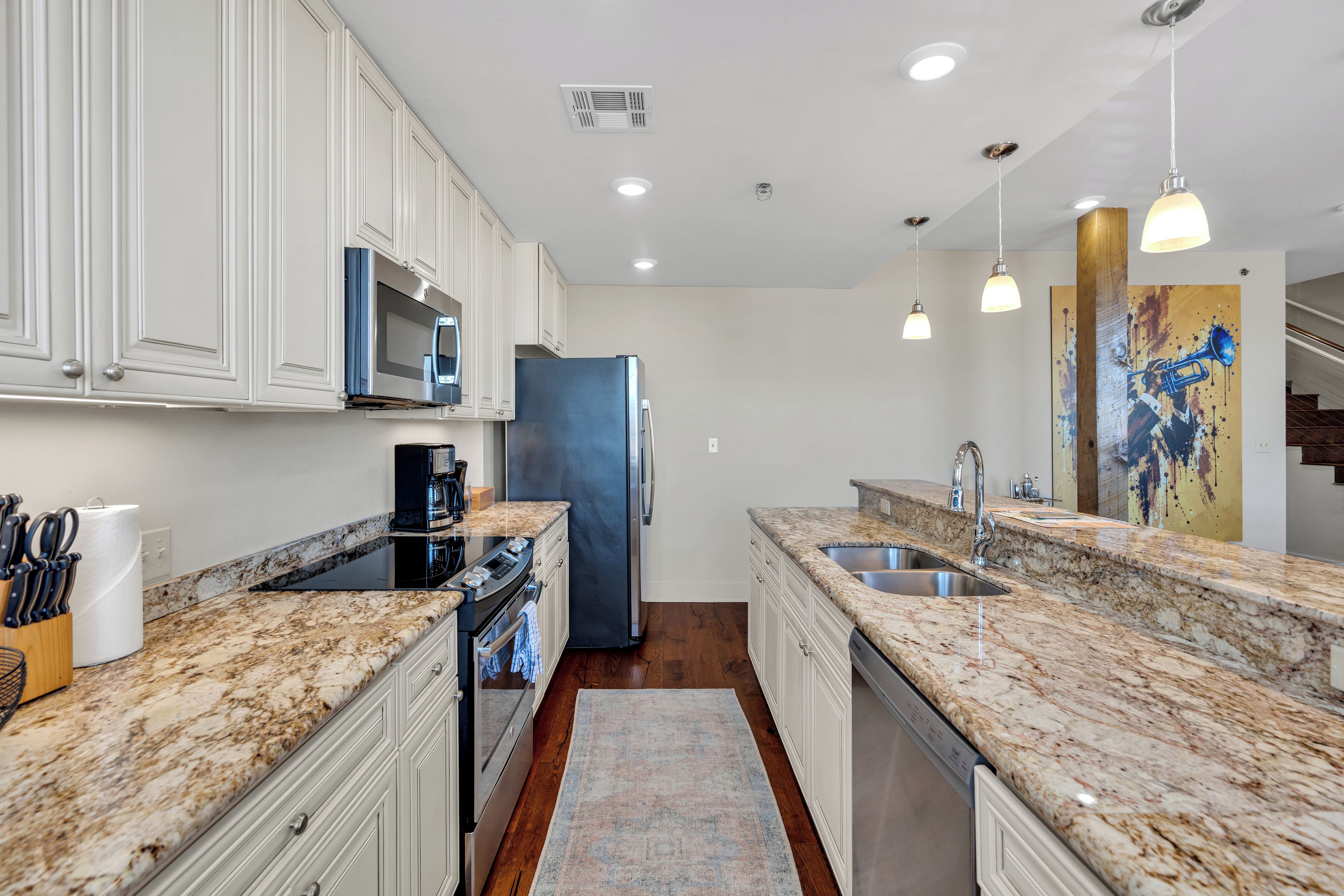 A modern kitchen with white cabinetry, a stainless steel refrigerator, and granite countertops.