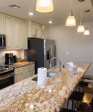 A modern kitchen with granite countertops, stainless steel appliances, and pendant lighting. - Upscale 2BR New Orleans vacation rental in Bywater with 3 king beds, sleeping 4 guests. Enjoy 2.5 baths at the historic Burgundy & Piety corner, near Crescent Park, Frenchmen Street & the French Quarter. (New Orleans)