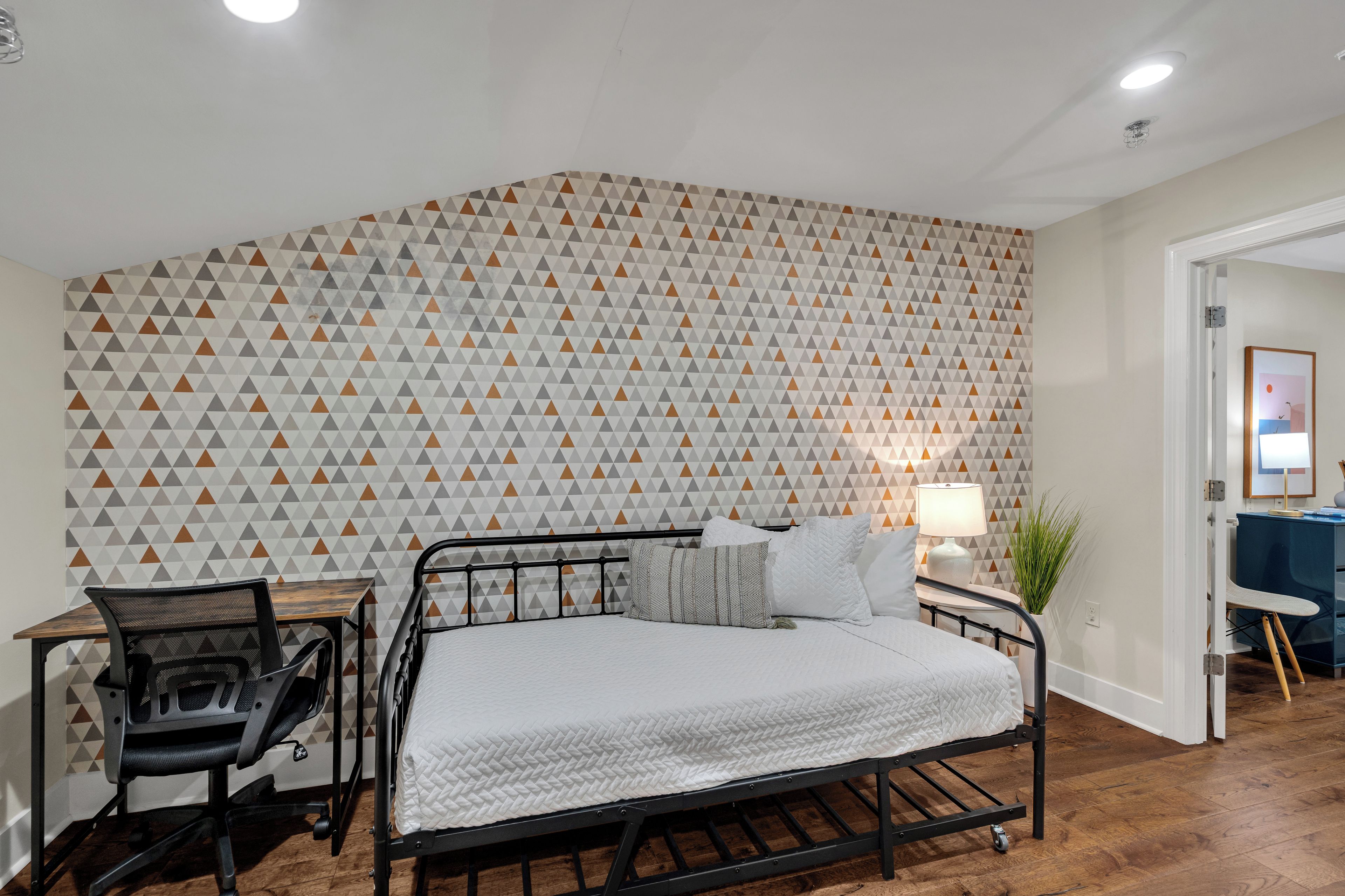 A bedroom with a bed, a desk, and a chair.