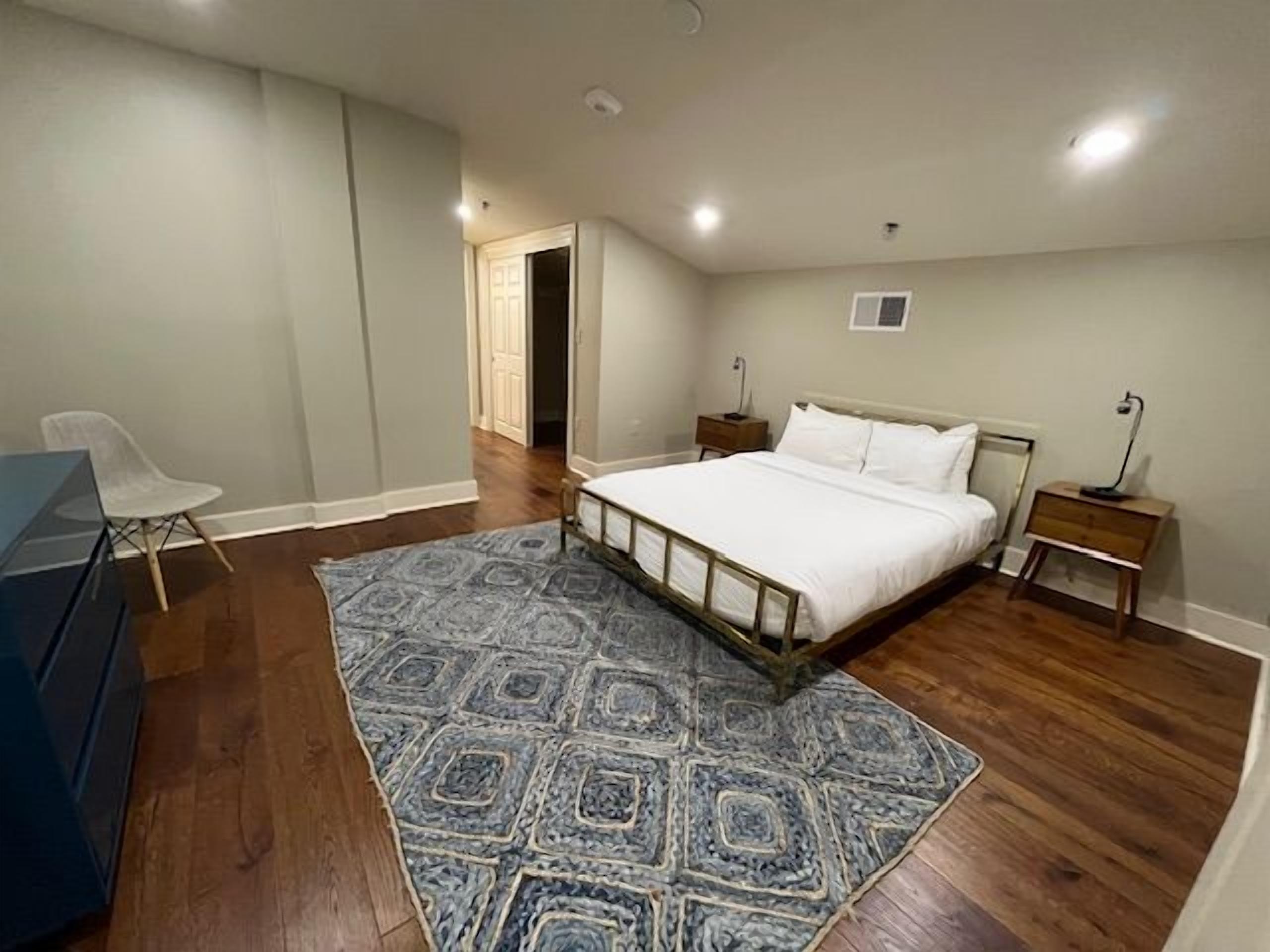 A bedroom with a bed, bedside tables, a chair, and a rug.