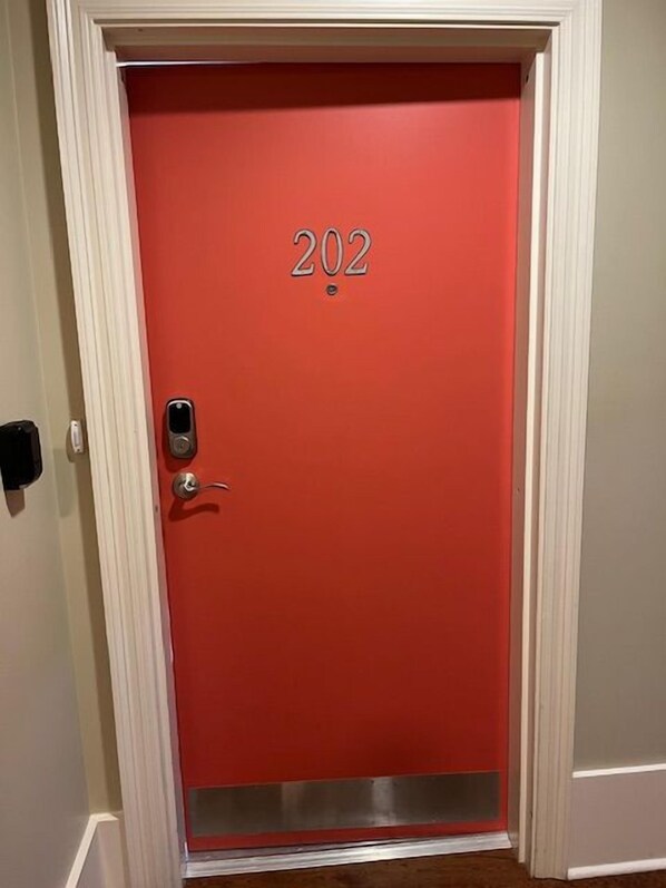 Una porta amb el número 202, un timbre i un llindar metàl·lic.