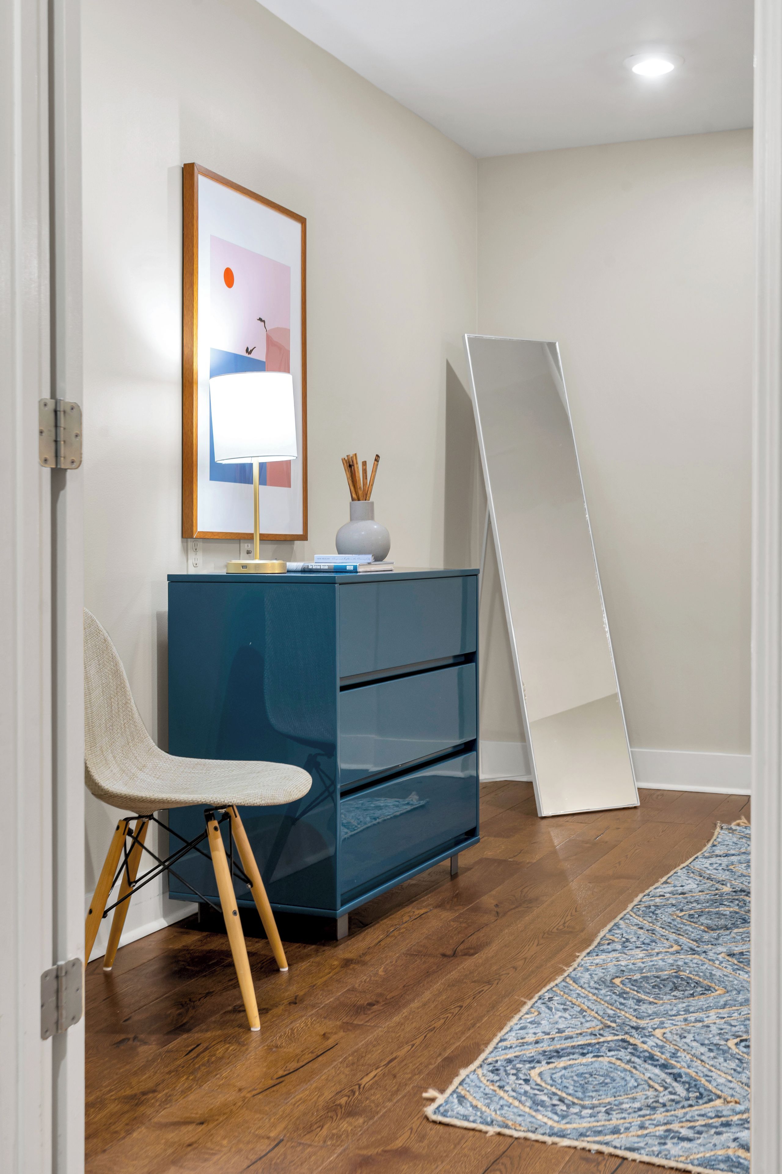 A room with a desk, chair, and a large whiteboard leaning against the wall.