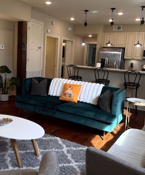 Een moderne woonkamer met een blauwgroene bank, een witte salontafel en een grijs vloerkleed.