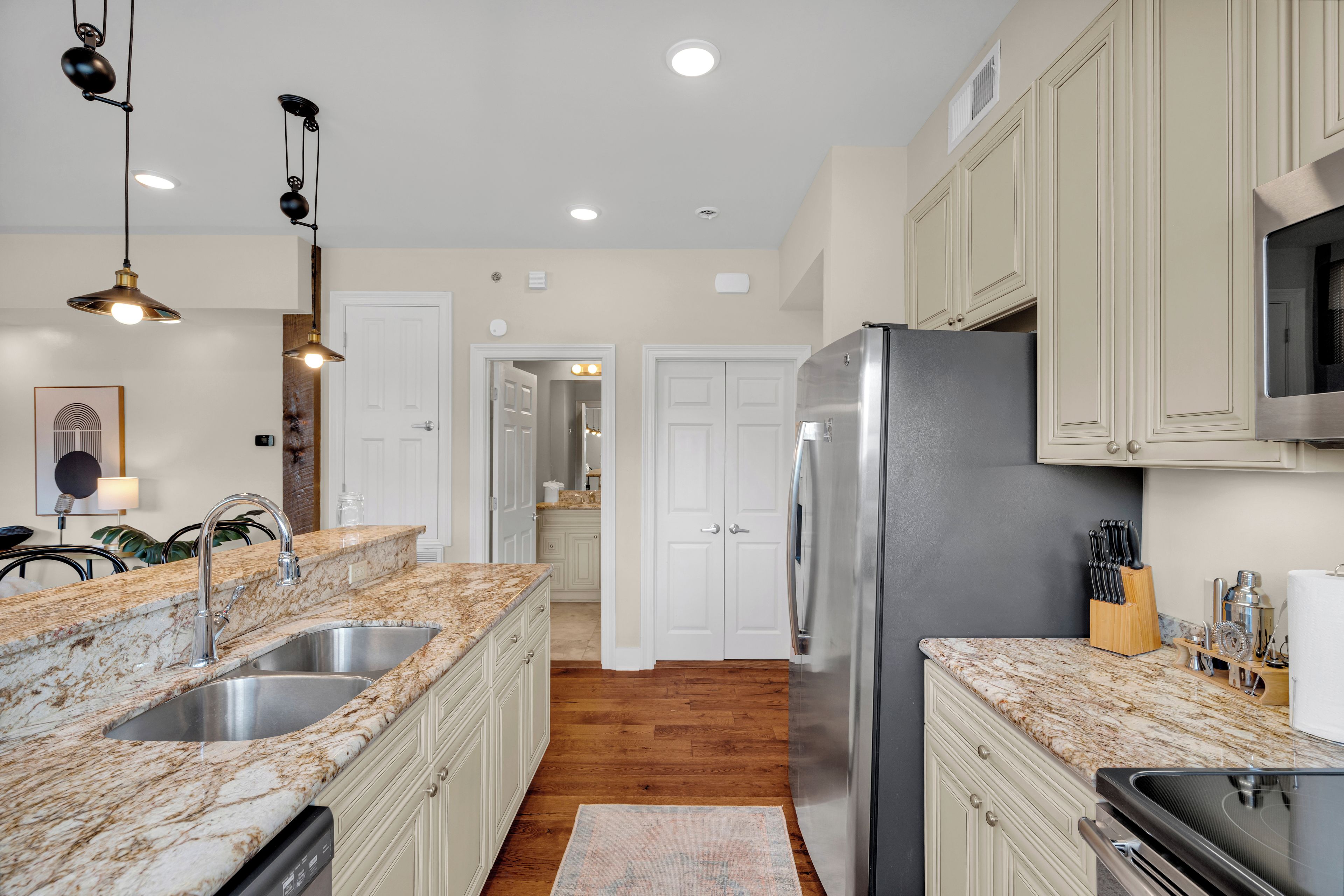 A modern kitchen with granite countertops, stainless steel appliances, and pendant lighting.