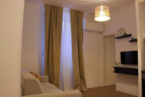 Una sala de estar con un sofá, un televisor y una lámpara colgante.