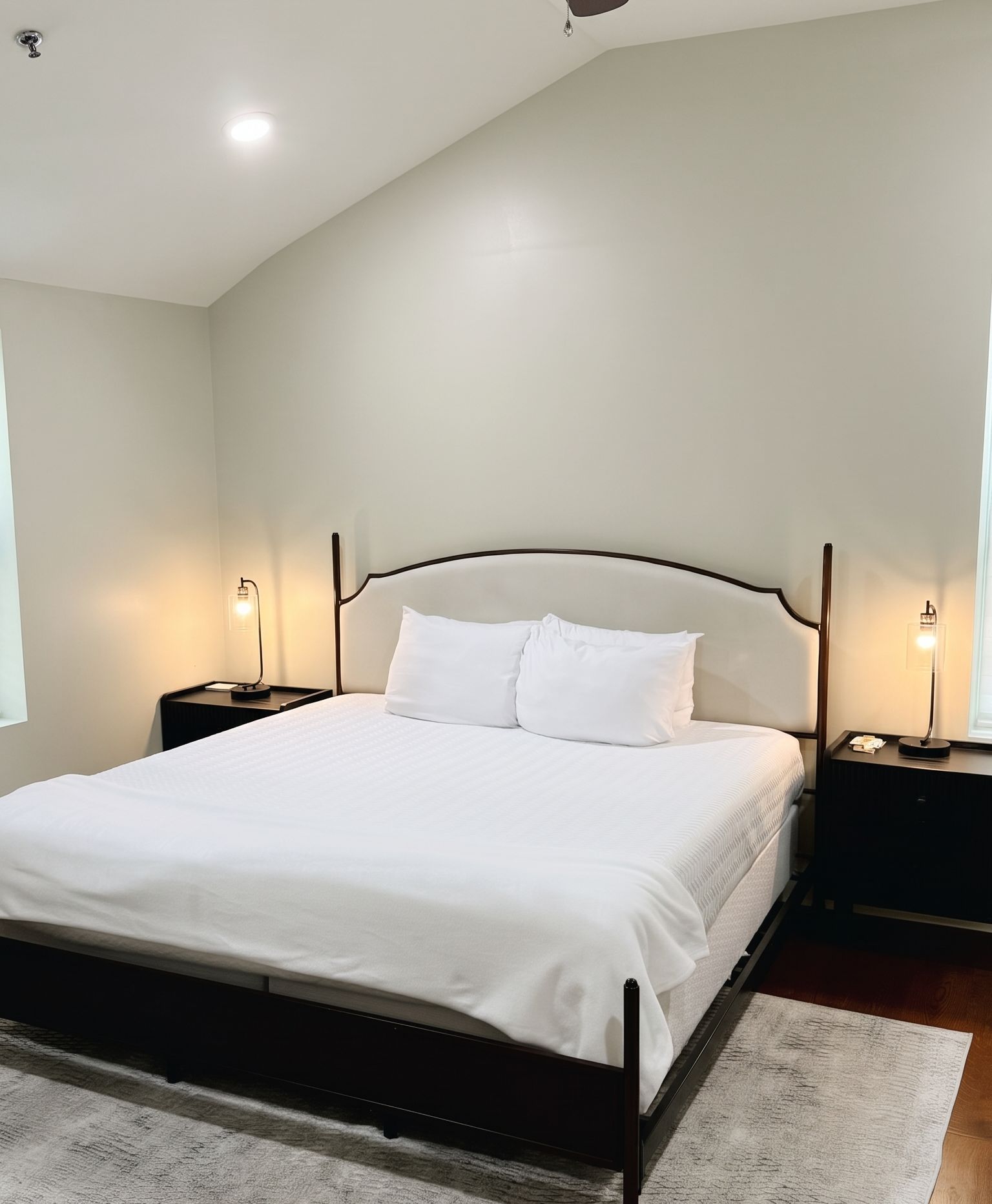 A bedroom with a bed, nightstands, and a ceiling light.